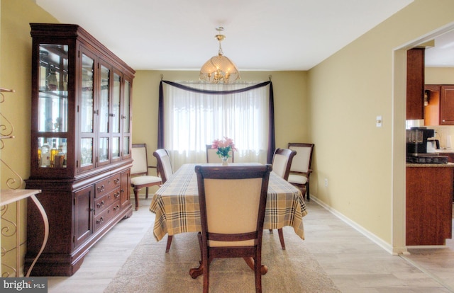 dining area with light wood-style floors, baseboards, and a notable chandelier