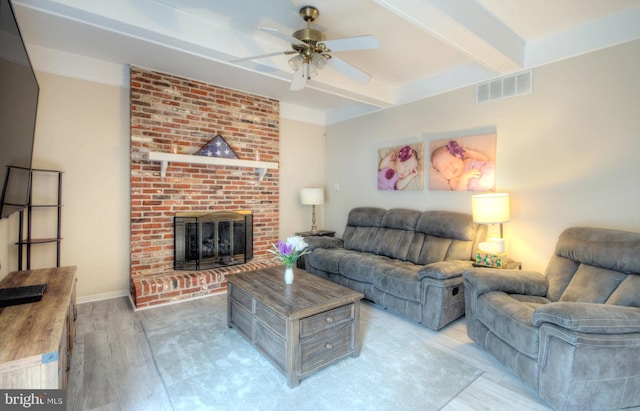 living room featuring a fireplace, light wood-style floors, a ceiling fan, beamed ceiling, and visible vents