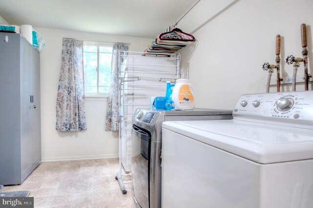 clothes washing area with laundry area, baseboards, and washer and dryer