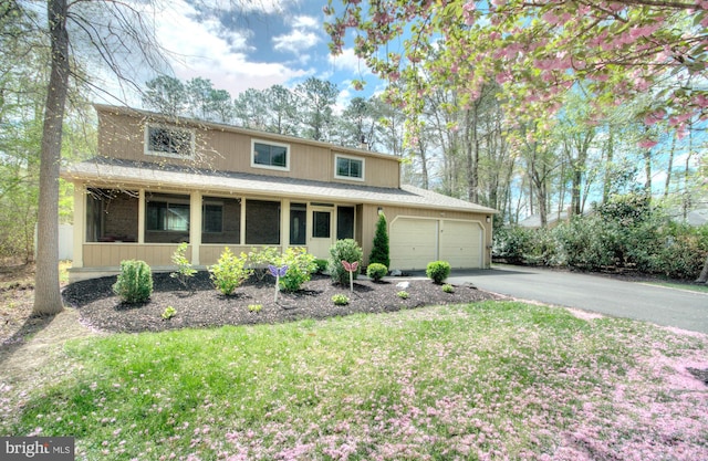 traditional home with driveway, a front lawn, a sunroom, and a garage