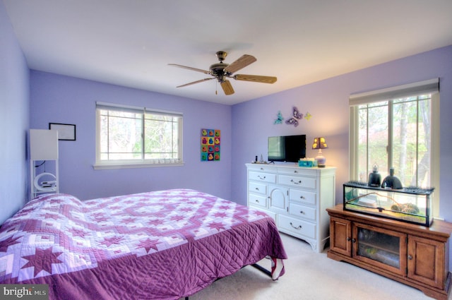 bedroom featuring light colored carpet, ceiling fan, and multiple windows