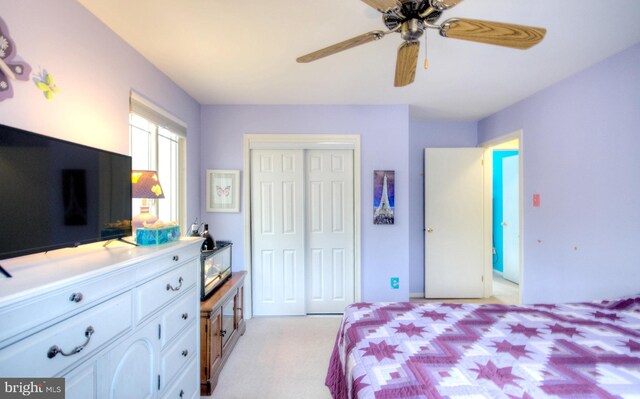bedroom with a closet, ceiling fan, and light colored carpet