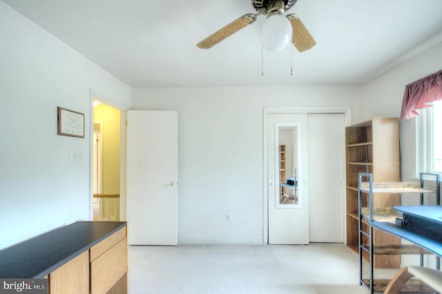 carpeted office with a ceiling fan