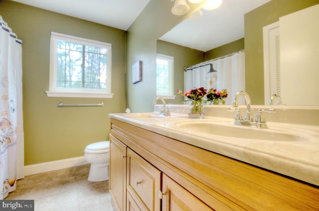bathroom featuring double vanity, tile patterned flooring, a sink, baseboards, and toilet