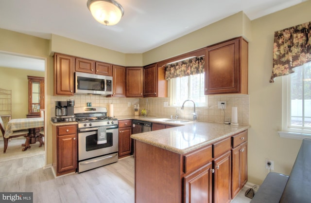kitchen with brown cabinetry, a sink, backsplash, and stainless steel appliances