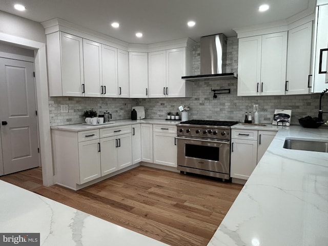 849 Glenn Cir, Wayne, PA 19087 - kitchen with wall chimney exhaust hood, high end range, a sink, decorative backsplash, and light wood-type flooring
