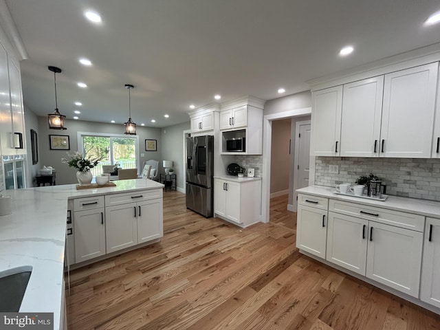 849 Glenn Cir, Wayne, PA 19087 - kitchen with stainless steel appliances, white cabinetry, tasteful backsplash, light wood-style floors, and hanging light fixtures