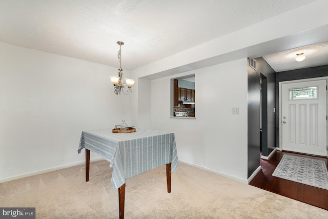dining room featuring carpet, baseboards, a chandelier, and a textured ceiling