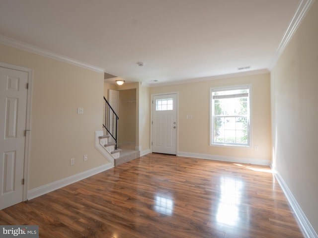 foyer featuring visible vents, baseboards, ornamental molding, wood finished floors, and stairs