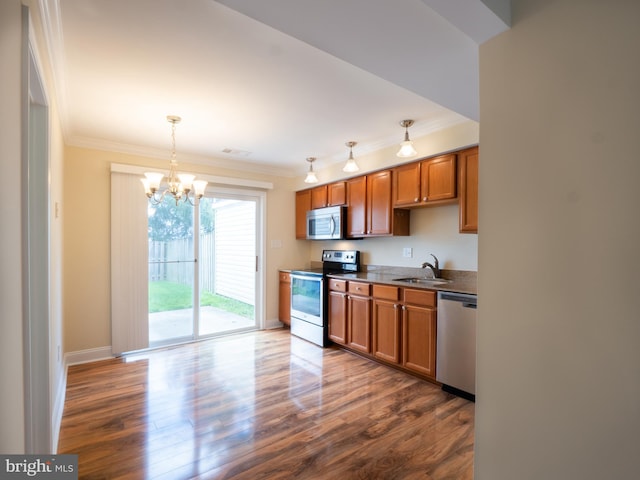 kitchen featuring brown cabinetry, a sink, crown molding, and appliances with stainless steel finishes