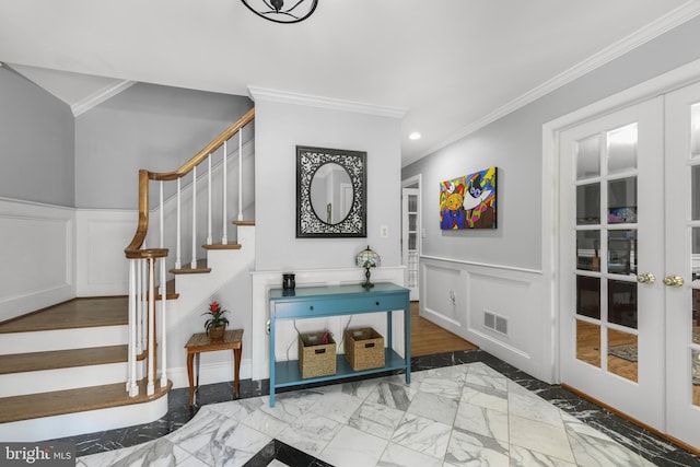 foyer entrance with marble finish floor, stairway, a decorative wall, and crown molding