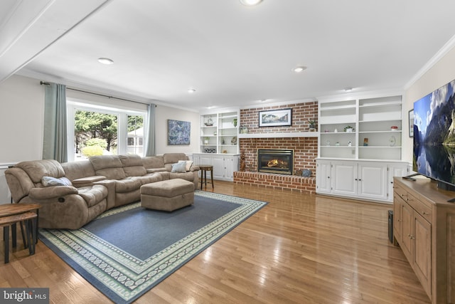 living area with built in features, light wood finished floors, ornamental molding, a brick fireplace, and recessed lighting