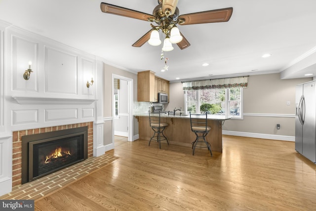 kitchen featuring stainless steel appliances, baseboards, a kitchen bar, a peninsula, and ornamental molding