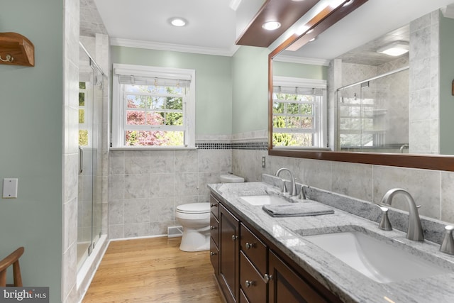 bathroom with ornamental molding, a stall shower, a sink, and tile walls
