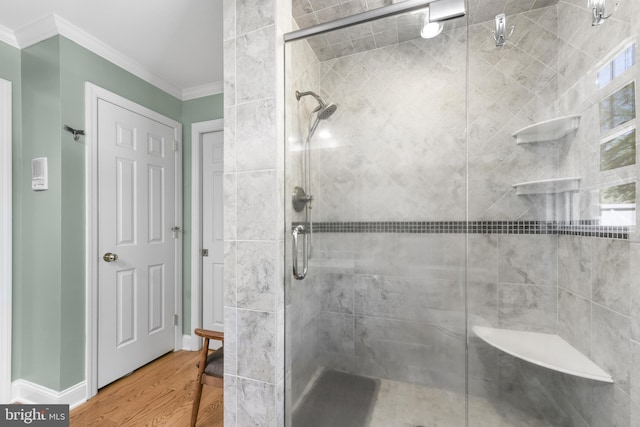 bathroom with baseboards, wood finished floors, crown molding, and a stall shower