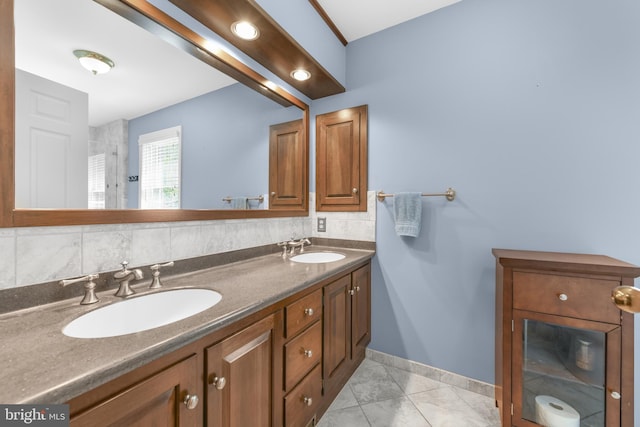 bathroom with double vanity, baseboards, and a sink