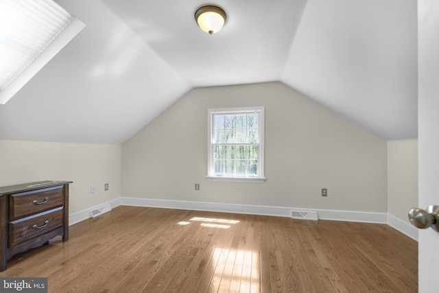 additional living space featuring lofted ceiling, baseboards, wood finished floors, and visible vents