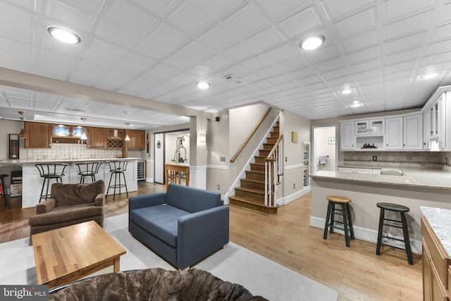 living area featuring light wood-style flooring, baseboards, recessed lighting, and stairs