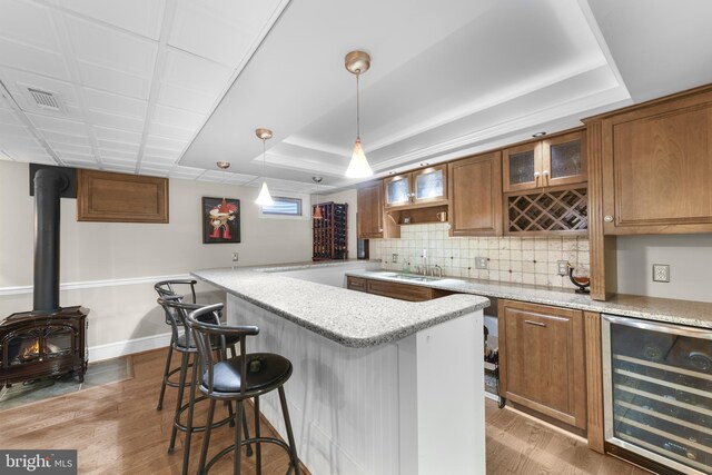 bar featuring a tray ceiling, light wood-style floors, and wine cooler