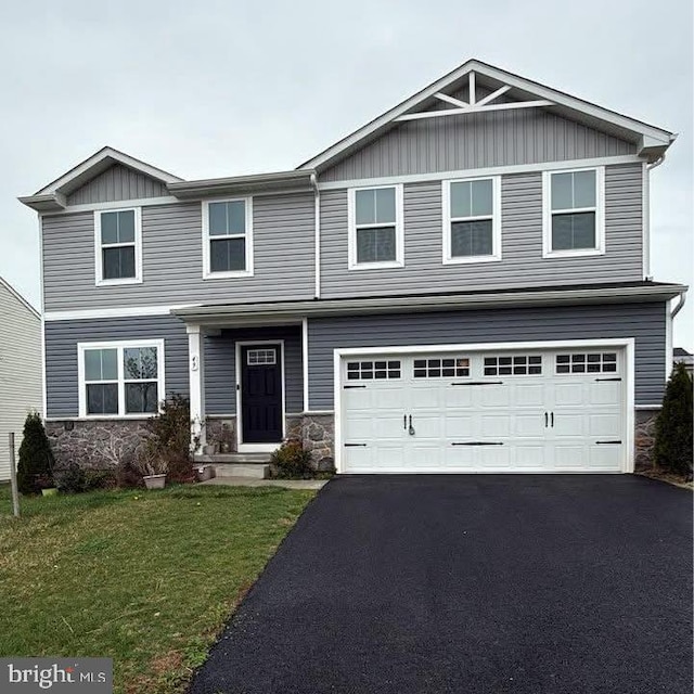 craftsman-style home with aphalt driveway, a front lawn, stone siding, and an attached garage