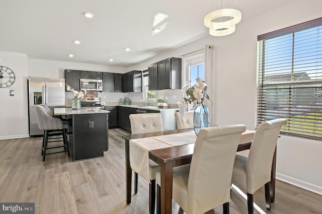 dining space featuring light wood-style flooring, recessed lighting, an inviting chandelier, and baseboards