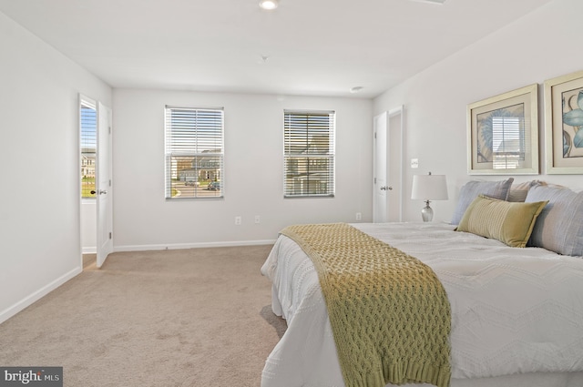 bedroom featuring light colored carpet, baseboards, and multiple windows