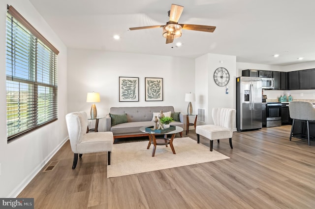 living room with light wood-type flooring, visible vents, and recessed lighting