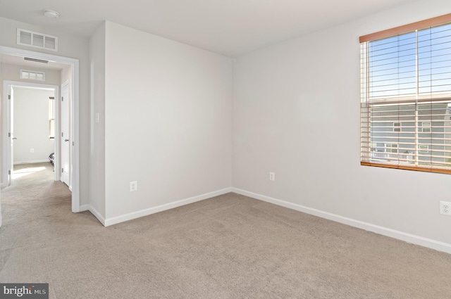 carpeted empty room featuring visible vents and baseboards