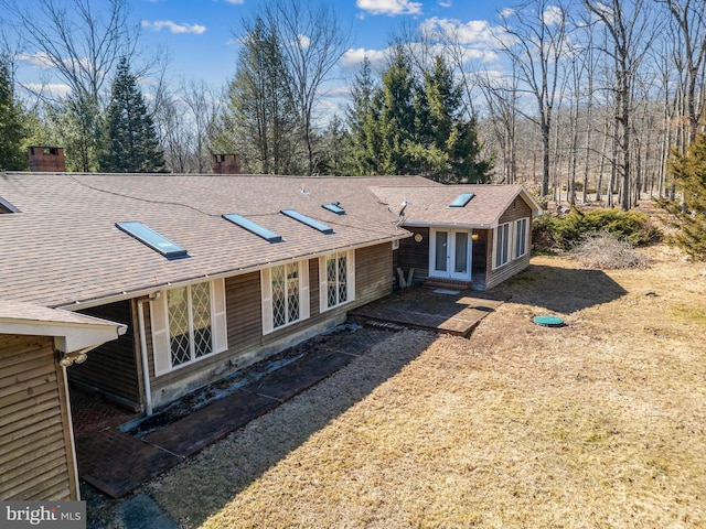 view of front of property with roof with shingles, french doors, and a chimney