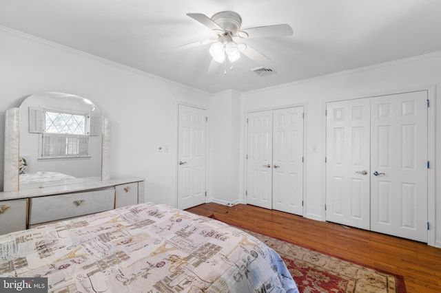 bedroom featuring ornamental molding, visible vents, and wood finished floors
