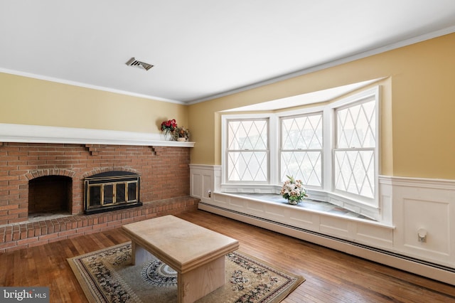 living room with visible vents, a baseboard radiator, wood-type flooring, and a wainscoted wall