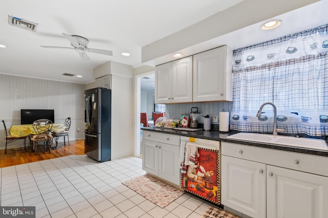 kitchen with freestanding refrigerator, dark countertops, visible vents, white dishwasher, and a sink