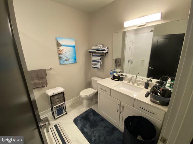 bathroom with a shower, toilet, baseboards, and vanity