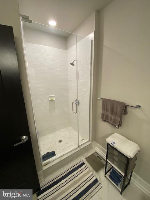 bathroom with a stall shower, baseboards, and marble finish flooring