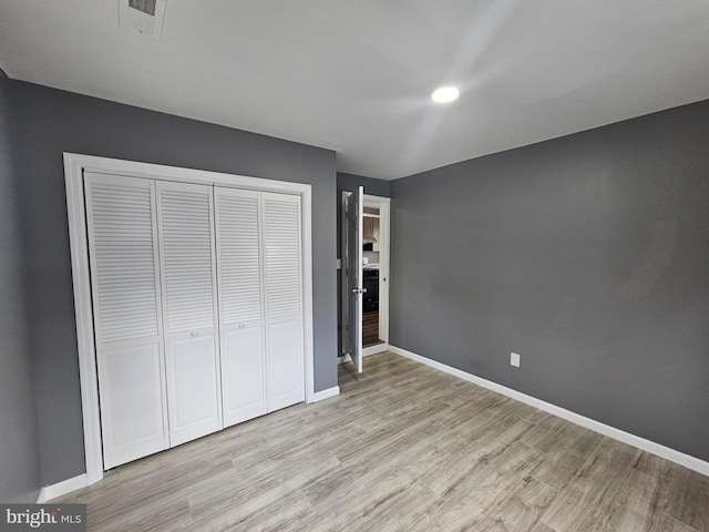 unfurnished bedroom featuring visible vents, baseboards, light wood finished floors, and a closet