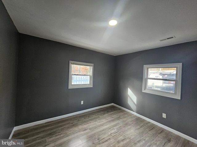 empty room featuring visible vents, baseboards, and wood finished floors