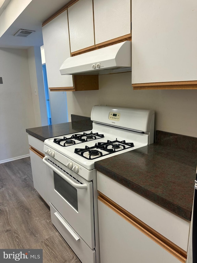 10206 Prince Pl Unit 4-204, Upper Marlboro, MD 20774 - kitchen with visible vents, dark countertops, under cabinet range hood, dark wood-type flooring, and white gas range oven