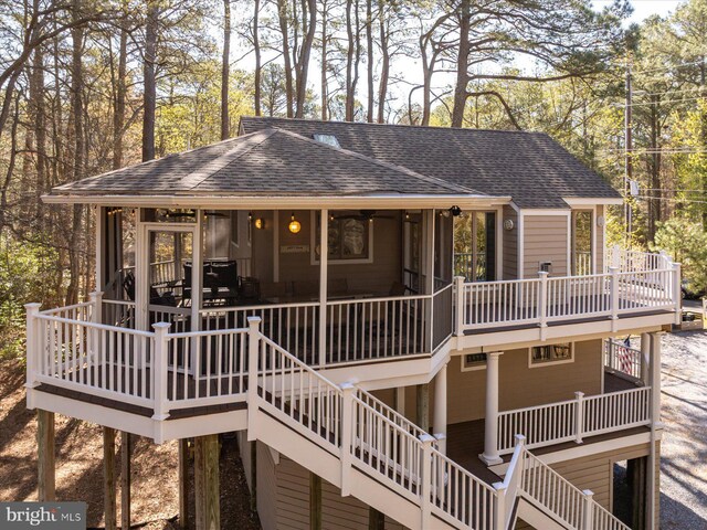 exterior space with a sunroom, a shingled roof, stairway, and a deck