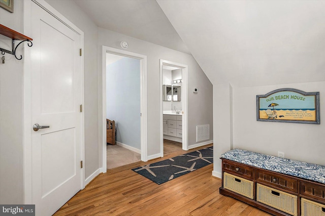 bedroom with vaulted ceiling, visible vents, a sink, baseboards, and light wood-style flooring