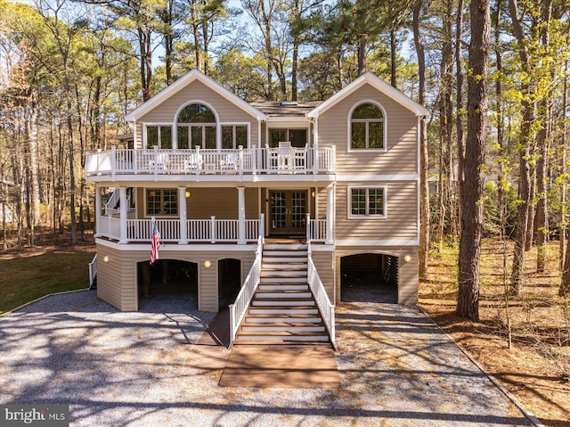 view of front of property with a wooden deck, a porch, gravel driveway, and stairway