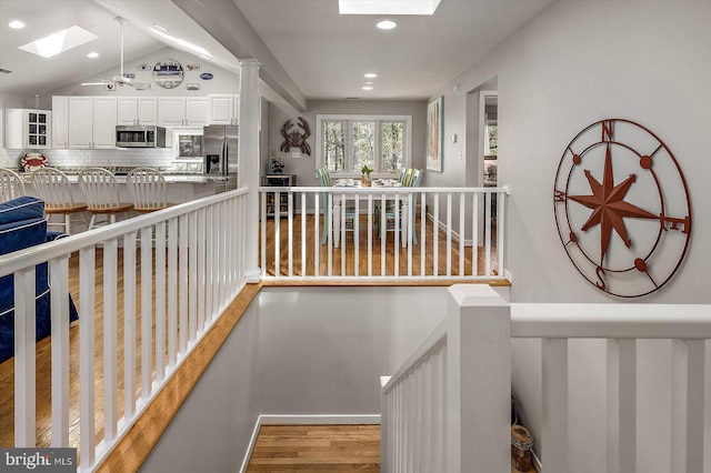 interior space featuring wood finished floors, lofted ceiling with skylight, and recessed lighting