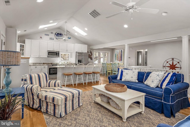 living room with light wood-style floors, visible vents, a skylight, and a ceiling fan