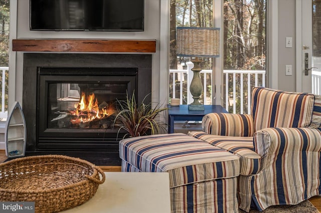 sitting room with a glass covered fireplace and wood finished floors