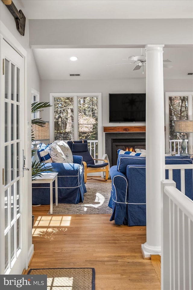 living room featuring wood finished floors, decorative columns, visible vents, and ceiling fan
