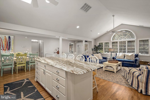 kitchen featuring open floor plan, a ceiling fan, visible vents, and a breakfast bar area
