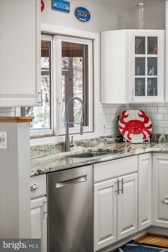 bar with decorative backsplash, dishwasher, and a sink