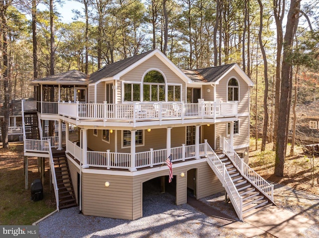 view of front of house featuring roof with shingles, a sunroom, stairway, and a deck
