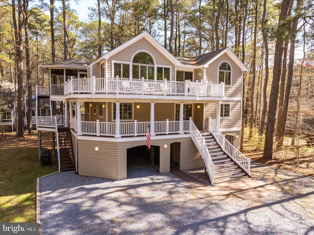 view of front facade featuring stairway, roof with shingles, driveway, and covered porch