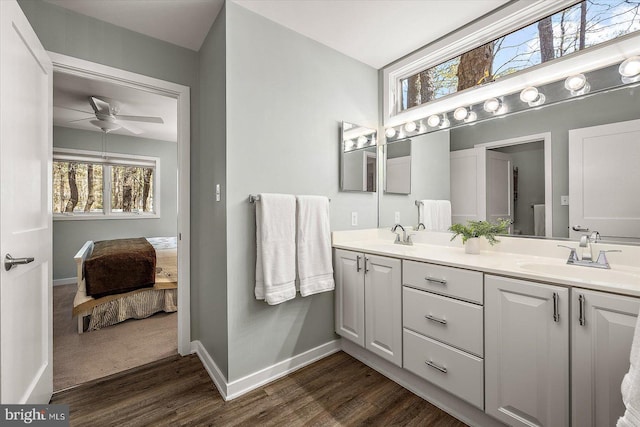 ensuite bathroom with wood finished floors, a ceiling fan, baseboards, and a sink