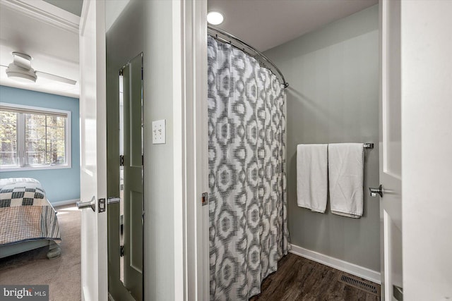 ensuite bathroom with wood finished floors, a shower with curtain, baseboards, ensuite bath, and visible vents